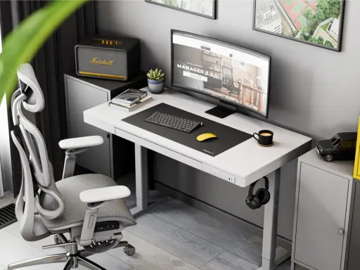 Ergonomiczne biurko do pracy przy komputerze z monitorem, klawiaturą i myszką. Obok stoi wygodny fotel biurowy i szafka z głośnikiem Marshall.