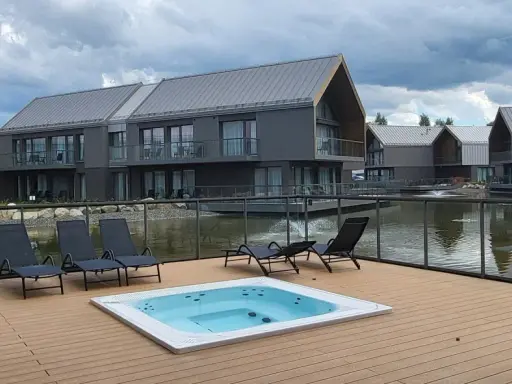 Relaks przy jacuzzi i basenie z widokiem na nowoczesne domki nad wodą. Idealne miejsce na wypoczynek w stylu termy Karkonosze.