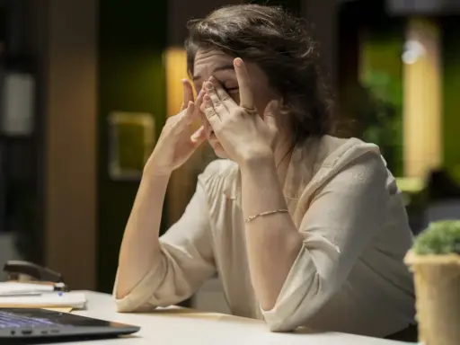 Eine Frau reibt sich erschöpft die Augen, die Arbeit am Laptop ist zu viel. Ich kann nicht mehr.