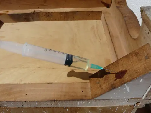 Jeringa inyectando líquido para eliminar carcoma en madera vieja.