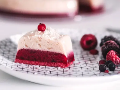 Deliciosa gelatina con agar agar, con capa roja de frutos rojos y capa superior cremosa, decorada con coco rallado y una baya.