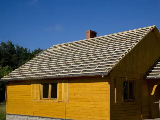 Żółty domek z widocznym pełnym deskowaniem dachu, przygotowanym pod pokrycie.