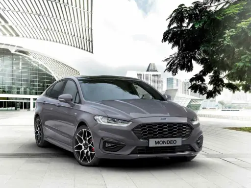 Ford Mondeo gris aparcado frente a un edificio moderno. Las medidas del Ford Mondeo son ideales para la ciudad.