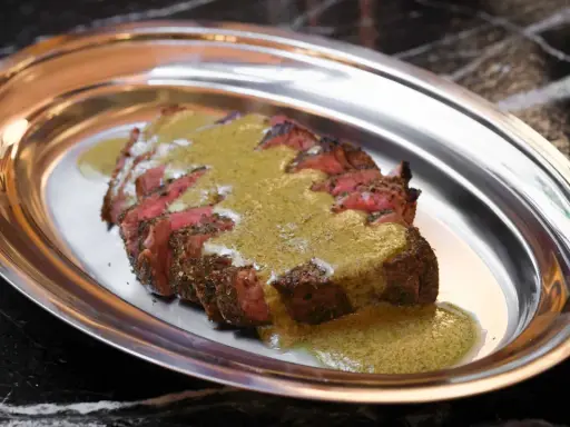 Tranché de bœuf, nappé d'une sauce verte, une spécialité parisienne servie sur un plateau métallique.