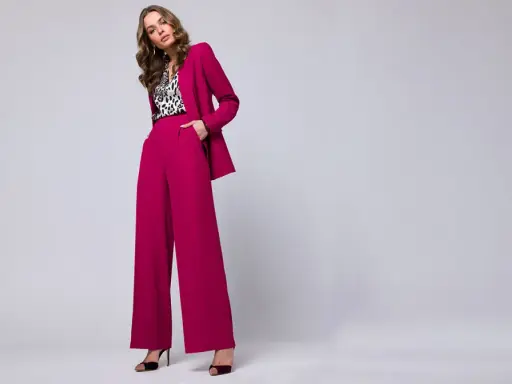 Elegancka stylizacja na chrzciny ze spodniami: fuksjowy garnitur z szerokimi nogawkami i bluzka w panterkę.