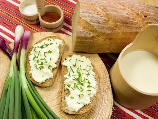 Chleb z twarogiem i szczypiorkiem, obok mleko i cebulka. Idealne składniki na zaprawę do wyrobu bryndzy.