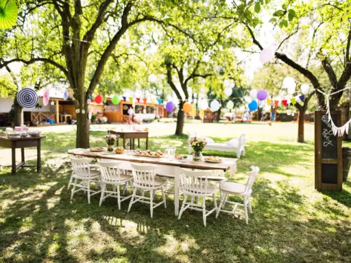 Une table dressée pour un repas en plein air, avec des guirlandes et des ballons, évoque une ambiance de deco jardin boheme chic.