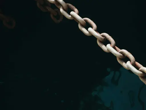 Chaîne rouillée d'une ancre de bateau, plongeant dans l'eau sombre et agitée.