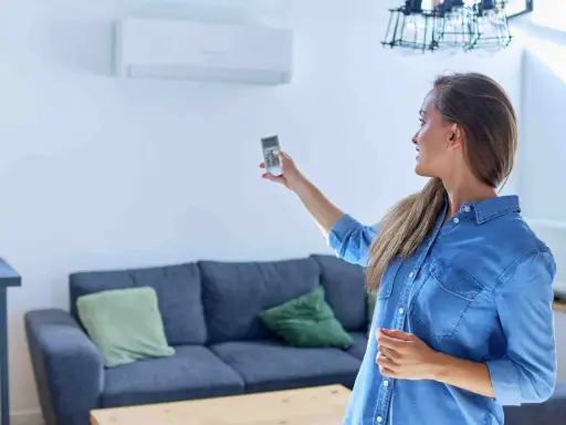 Mujer ajustando el sistema de climatización con un control remoto.