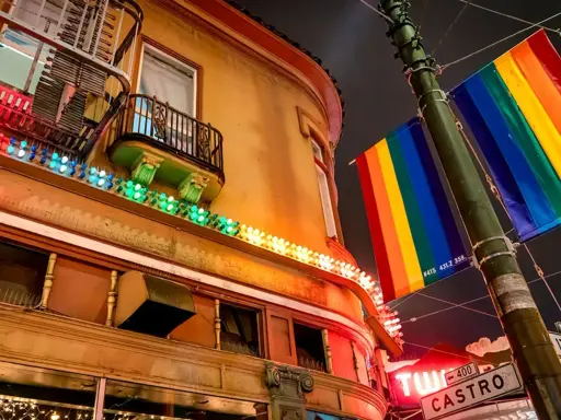 Rainbow flags fly proudly in the gayest city in America, illuminating a building with colorful lights.