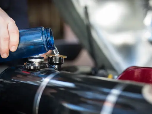 Maintenir le moteur 4 temps en bon état : on verse du liquide de refroidissement bleu dans le réservoir.