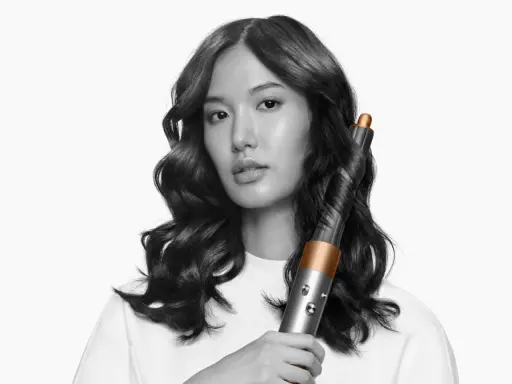 Frauenhaar wird mit einem Airwrap-Lockenstab zu perfekten Wellen geformt.
