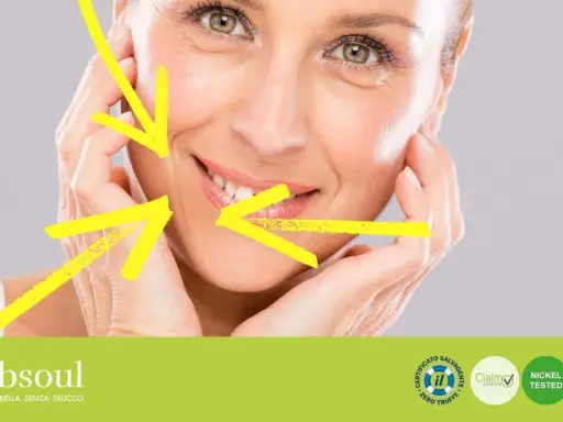 Primo piano di un volto femminile con rughe d'espressione, evidenziate da frecce gialle. Il trucco leggero esalta la bellezza naturale.