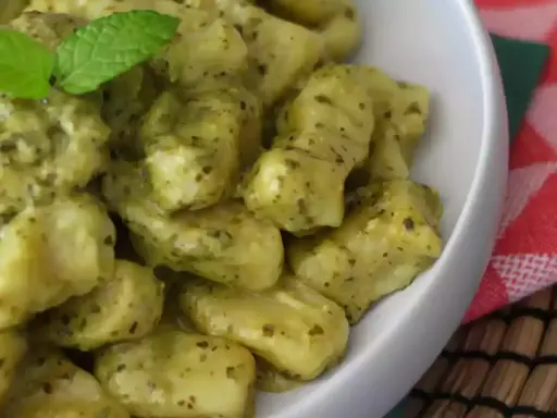 En skål med krämig italiensk gnocchi med pesto, toppad med färsk mynta. Ett perfekt italiensk gnocchi recept för en snabb och god middag.