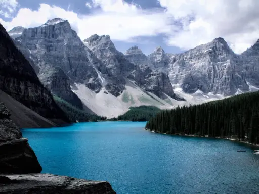 Türkisblaue See vor majestätischen Bergen, ein Traumziel für August-Reisen.