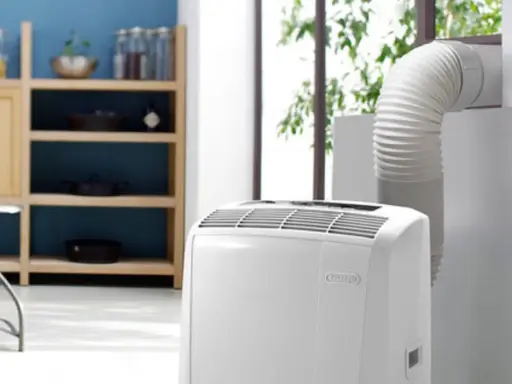 Climatiseur Rowenta portable, avec son tuyau d'évacuation dirigé vers une fenêtre. Un meuble de cuisine est visible à gauche.