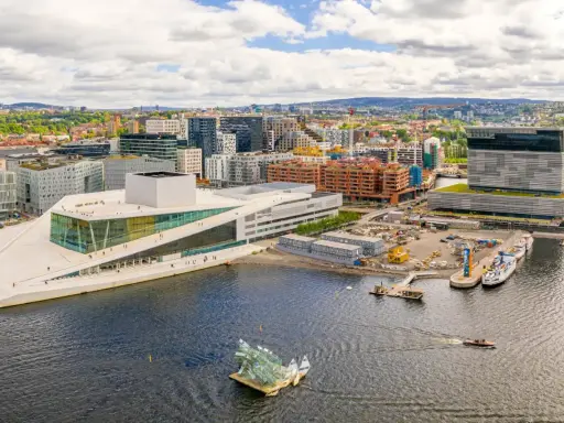 Il porto di Oslo con l'Opera House e moderni edifici. Barche navigano nell'acqua scura.