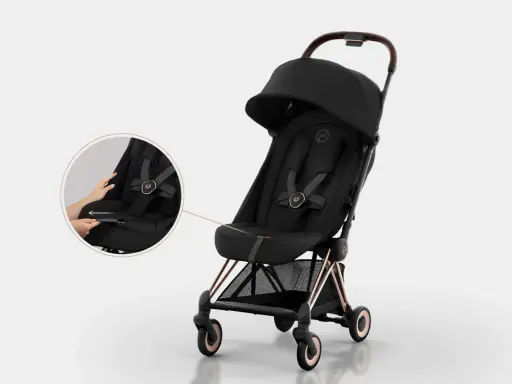 Elegancki czarny wózek Cybex Coya z miedzianymi detalami. Widoczna lupa pokazuje łatwe zapinanie pasów.