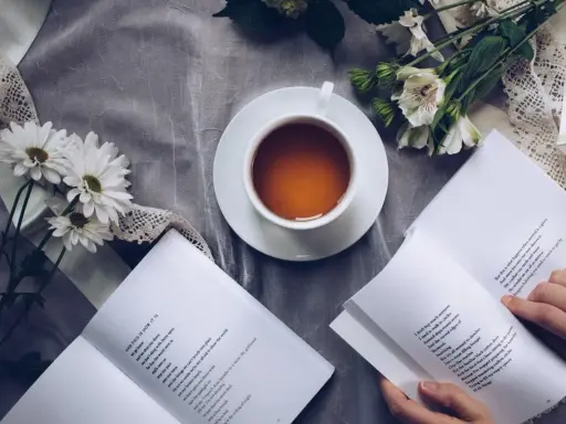 Eine Tasse Tee, Blumen und ein Buch mit einem wehmütigen Gedicht.