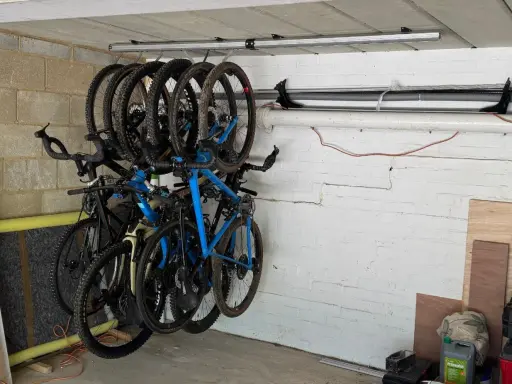 Système de rangement astucieux pour vélos dans un garage, plusieurs vélos suspendus au plafond pour optimiser l'espace.