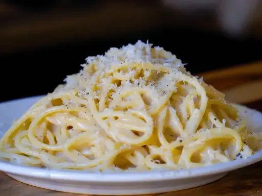 Pyszne cacio e pepe, czyli spaghetti z serem i pieprzem, posypane startym parmezanem.