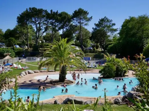 Disfruta de un día soleado en el camping de País Vasco, con una piscina refrescante y gente relajándose en tumbonas.