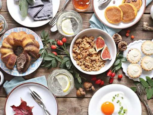 Leckere Brunch-Idee: Marmorkuchen, Müsli, Pancakes, Obst und ein Spiegelei auf rustikalem Holztisch.