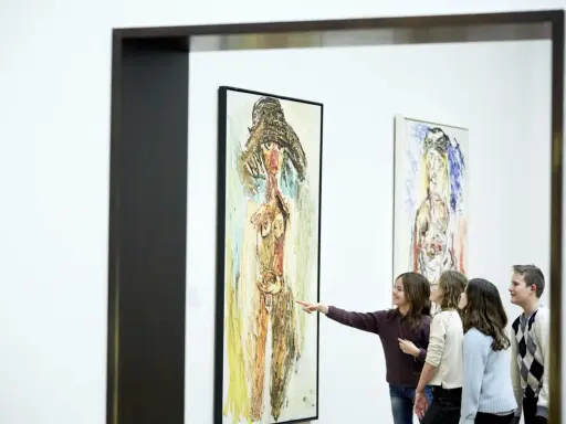 A group of children admire a painting in the style of the cobra art movement, with one girl pointing at the abstract figure.