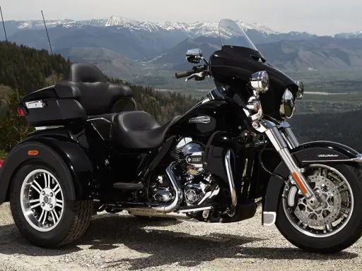 Harley-Davidson negro de tres ruedas aparcado en un paisaje montañoso. Recuerda que las motos de tres ruedas necesitan carnet de moto.