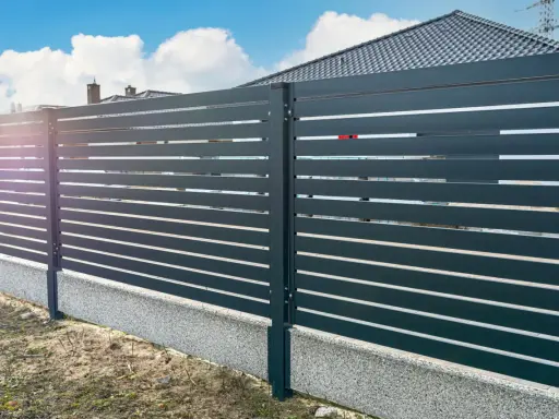 Nowoczesne ogrodzenie z poziomych paneli, osadzone na betonowym cokole. To świetne rozwiązanie co zamiast podmurówki pod ogrodzenie, zapewniające estetykę i trwałość.