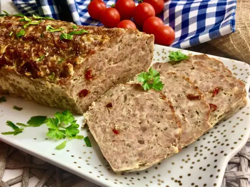 Pyszna pieczeń rzymska na kanapki, pokrojona w plastry, ozdobiona natką pietruszki. Idealna na śniadanie lub kolację.