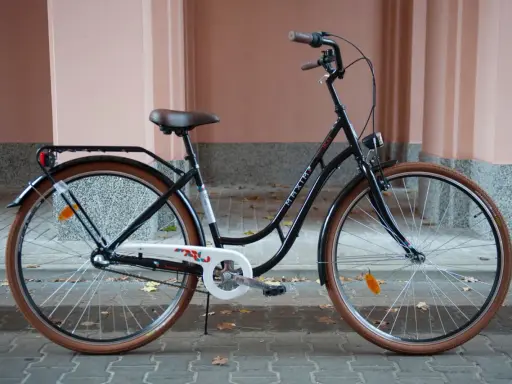 Elegancki, czarny rower do miasta z brązowymi oponami i wygodnym siodełkiem. Idealny na codzienne dojazdy.
