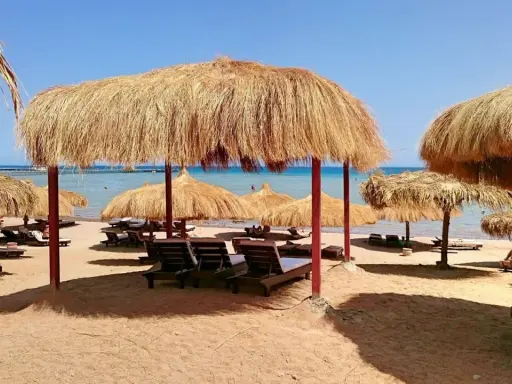 Słoneczna plaża z leżakami i parasolami z trawy. Idealne miejsce na relaks w stylu caves beach resort.