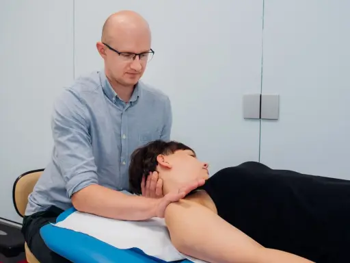 Osteopata wykonuje terapię manualną szyi pacjentki. Czy osteopata jest lekarzem? To pytanie często zadawane przez pacjentów.
