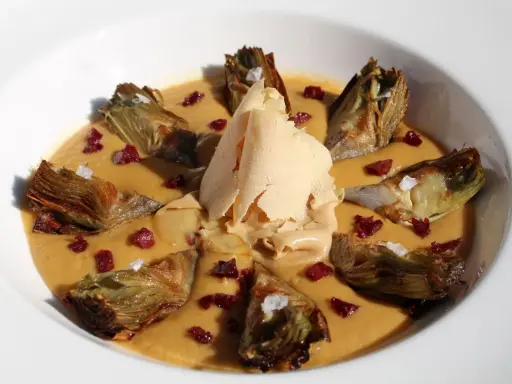 Delicioso guiso de alcachofas con trocitos de jamón y una lámina crujiente de queso.