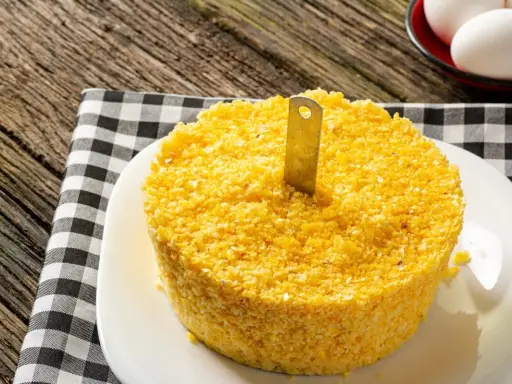 Un pastel de maíz amarillo con un cuchillo insertado, listo para servir. Una guía visual para como hacer cous cous.