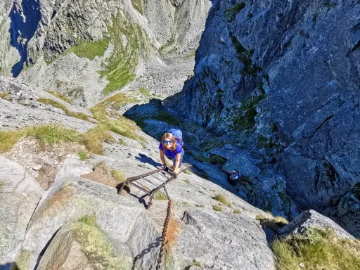 Kobieta wspina się po drabinie na Orlej Perci. Czas przejścia zależy od kondycji i pogody.