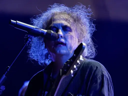 Robert Smith, en av medlemmar av The Cure, sjunger vid en mikrofon med sitt karaktäristiska hår.