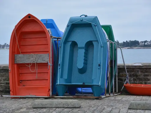 Plusieurs petites embarcations colorées, dont une annexe orange, sont rangées sur un quai.