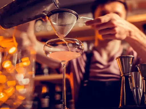 Un barman verse un cocktail d'un shaker dans un verre. C'est ainsi qu'un shaker sert à mélanger et refroidir les boissons.