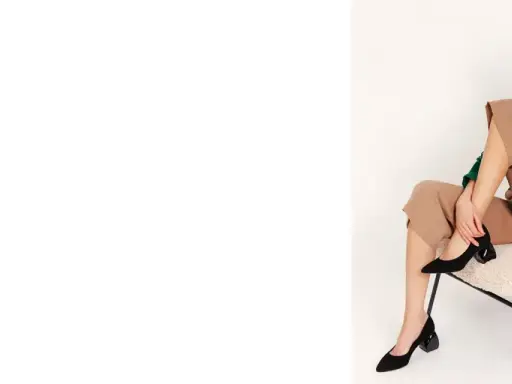 Eleganckie czarne czółenka na geometrycznym obcasie to idealne buty na jesień. Modelka prezentuje je w stylizacji z beżowymi spodniami i zieloną bluzką.