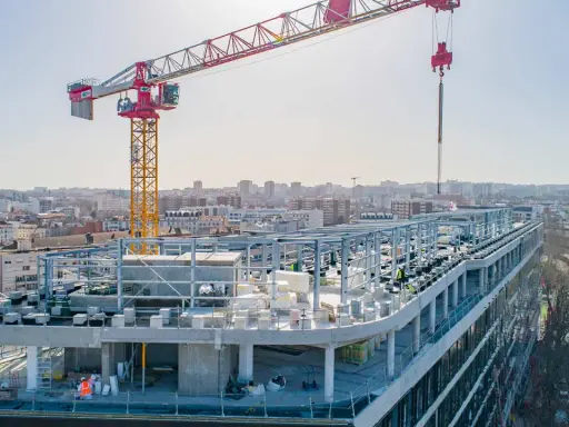 Grue de chantier sur un bâtiment en construction rapide, avec une ville en arrière-plan.