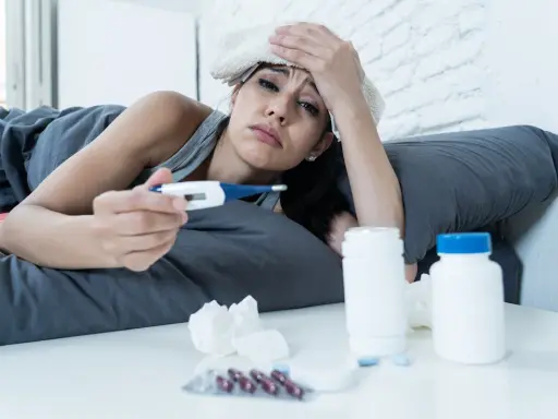 Donna malata a letto con termometro e medicine, preoccupata per i ciproxin effetti collaterali.