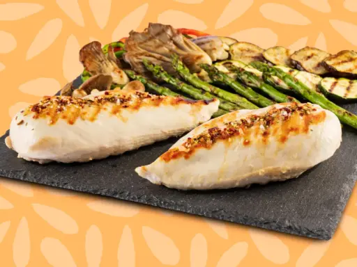 Dos jugosas pechugas de pollo a la parrilla, sazonadas con especias, acompañadas de espárragos, calabacín y champiñones.