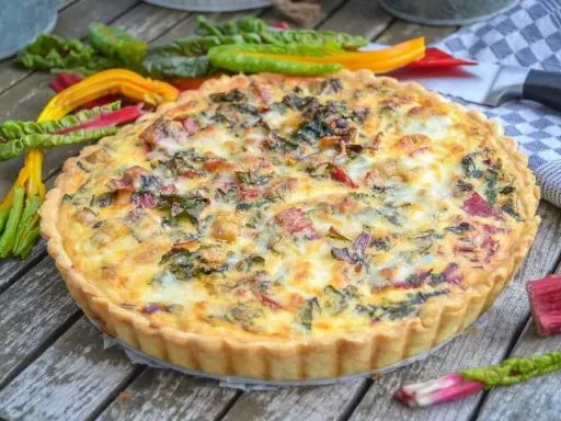Herzhafte Quiche mit buntem Mangold und knusprigem quiche teig auf Holztisch, garniert mit frischem Mangold.