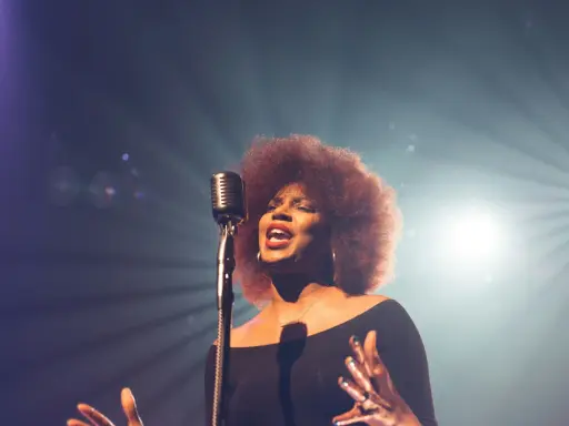 Kobieta z burzą afro włosów śpiewa do mikrofonu, jej głos jest niczym unchained melody, wolny i pełen emocji.