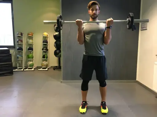 Mann macht Langhantel Curls im Fitnessstudio. Er trainiert seine Bizeps.