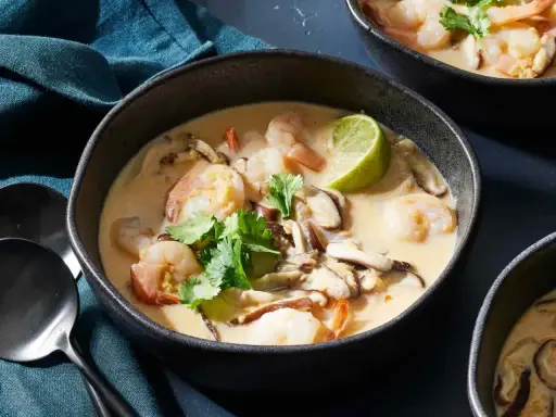 En skål med krämig tom kha gai med räkor, svamp och lime. En smakrik thailändsk soppa.