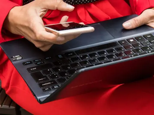 Besorgte Person prüft ihr Smartphone, nachdem ihr t-online Mail gehackt wurde. Sie hält es über eine Tastatur.