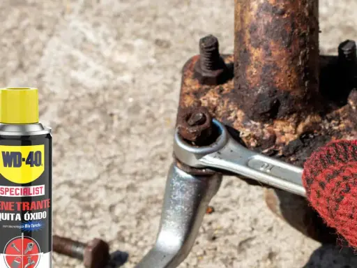 WD-40 ayuda a sacar tornillo roto de pieza oxidada. Llave inglesa y guante rojo en acción.